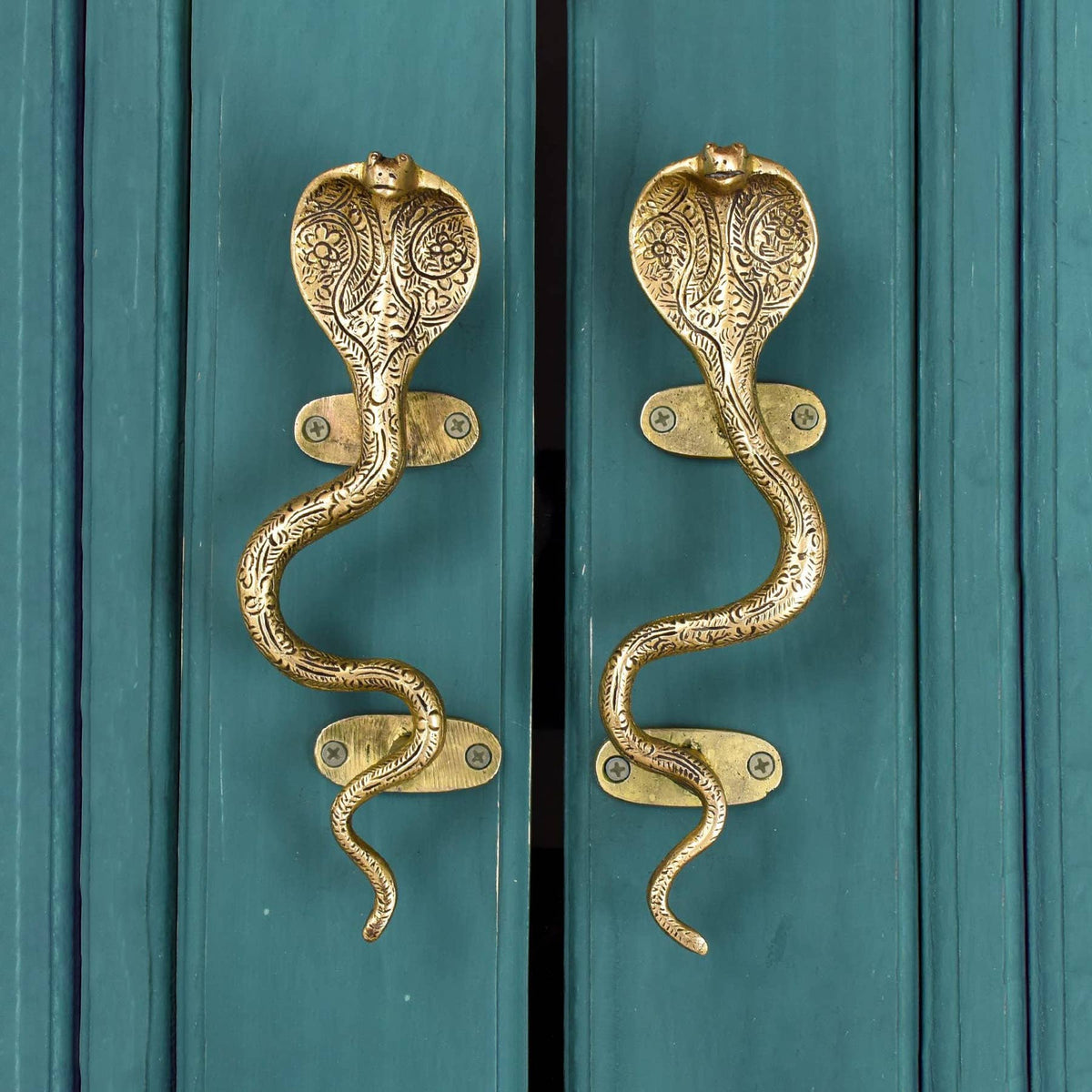Two brass cobra pulls with paisley-engraved hoods mounted on teal wooden doors – Spitfire Girl