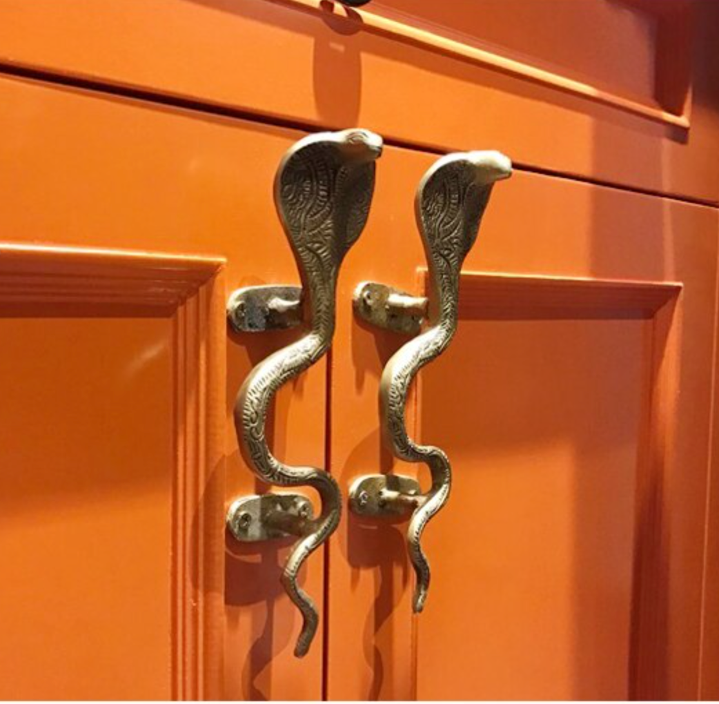 Facing pair of brass snake handles installed on orange kitchen cabinet doors – Spitfire Girl