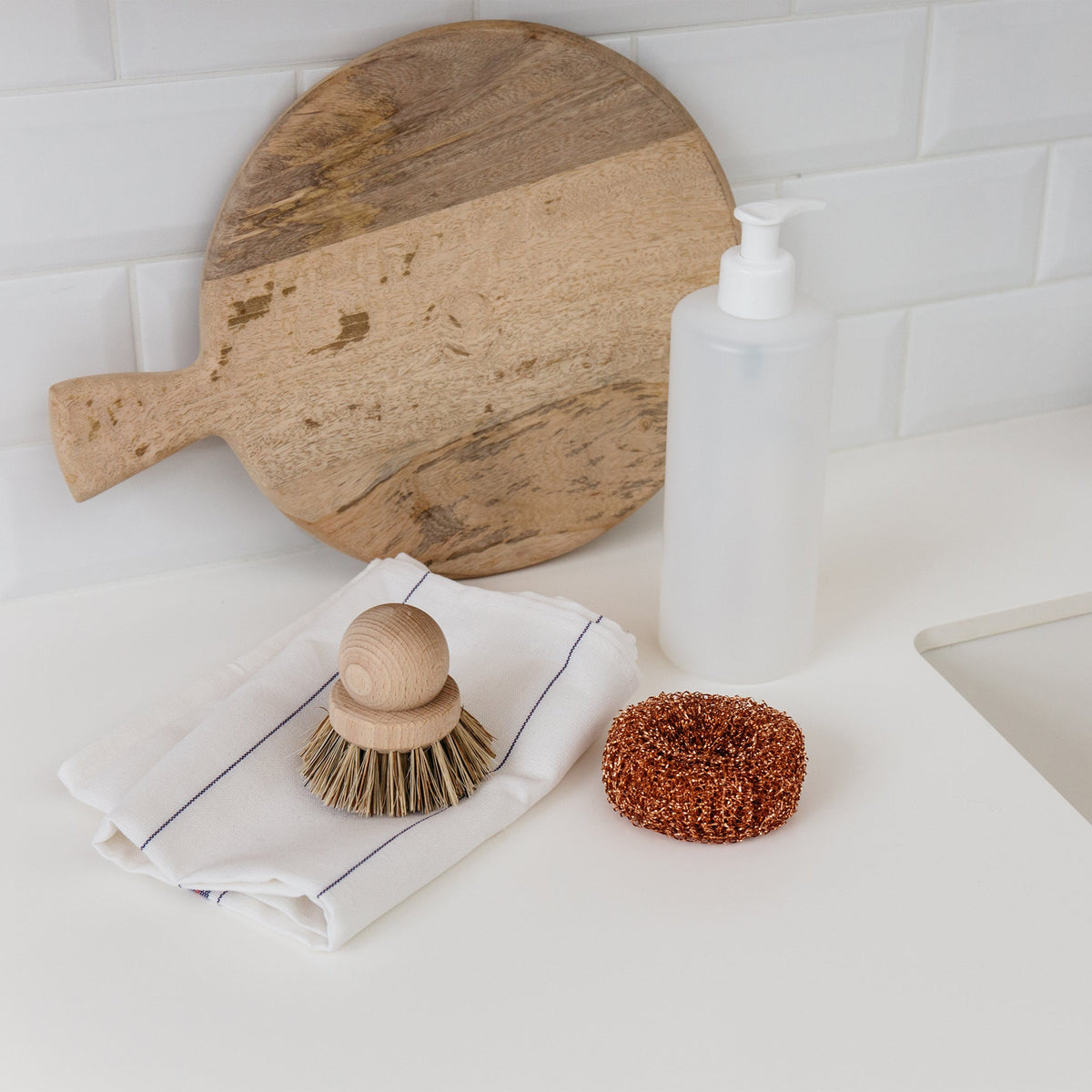 Copper scouring ball beside a wooden dish brush and chopping board next to the sink – Andrée Jardin
