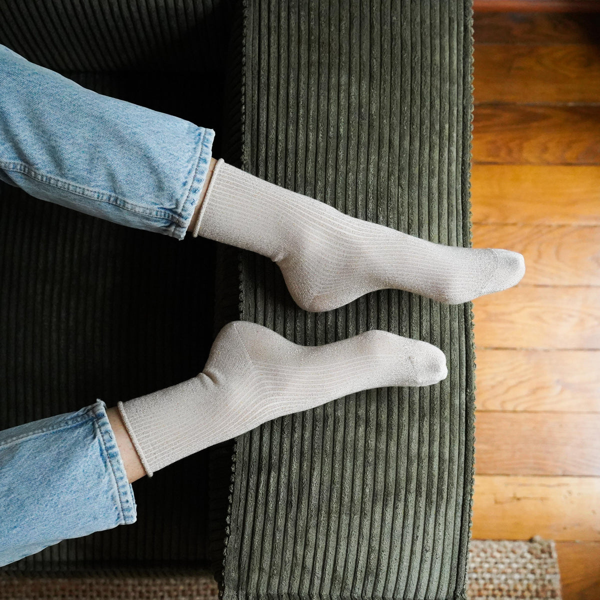 Pale beige lurex socks worn with jeans on a green corduroy sofa – KLUE