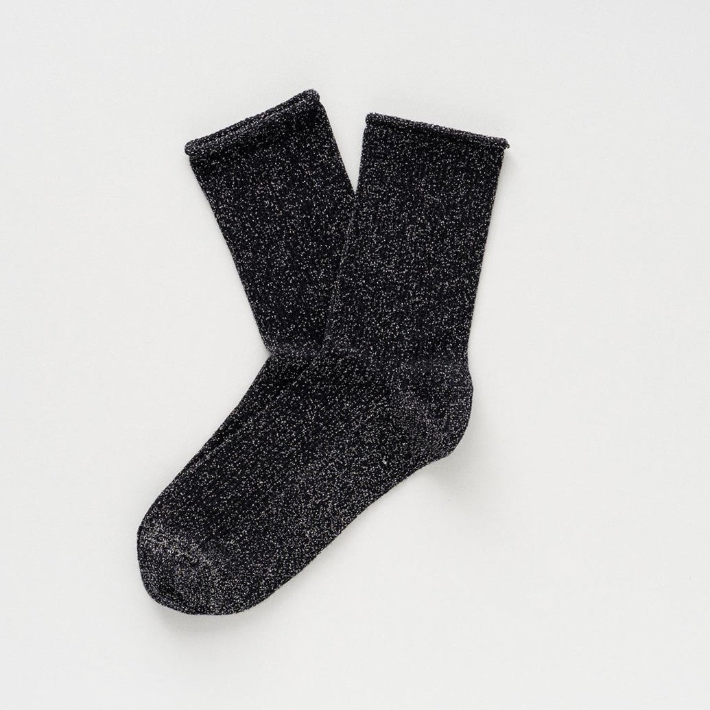 Black socks with a silver lurex shimmer, laid flat to show the rolled cuffs – KLUE