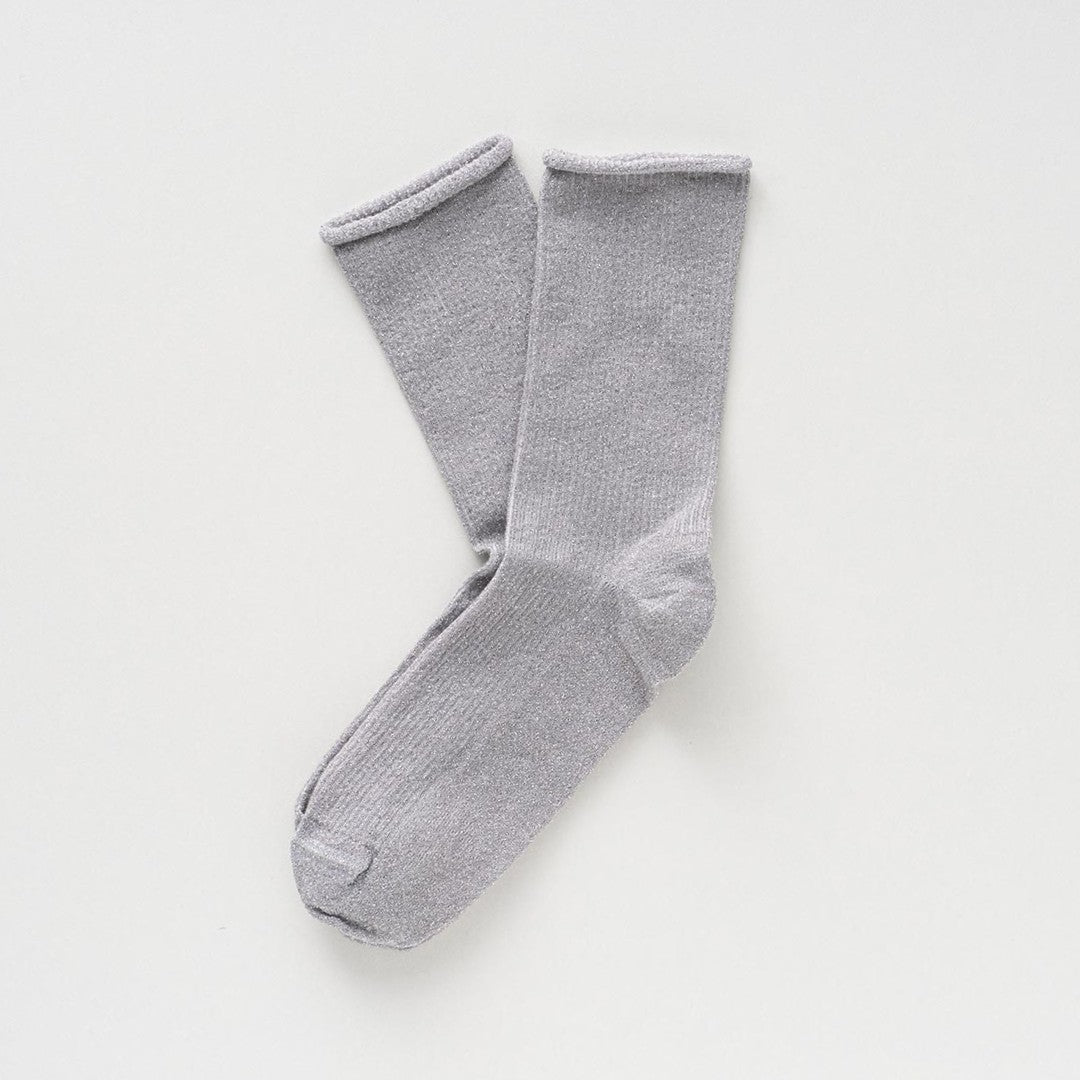 Light silver-grey socks with a soft glitter, laid flat to show the rolled cuffs – KLUE