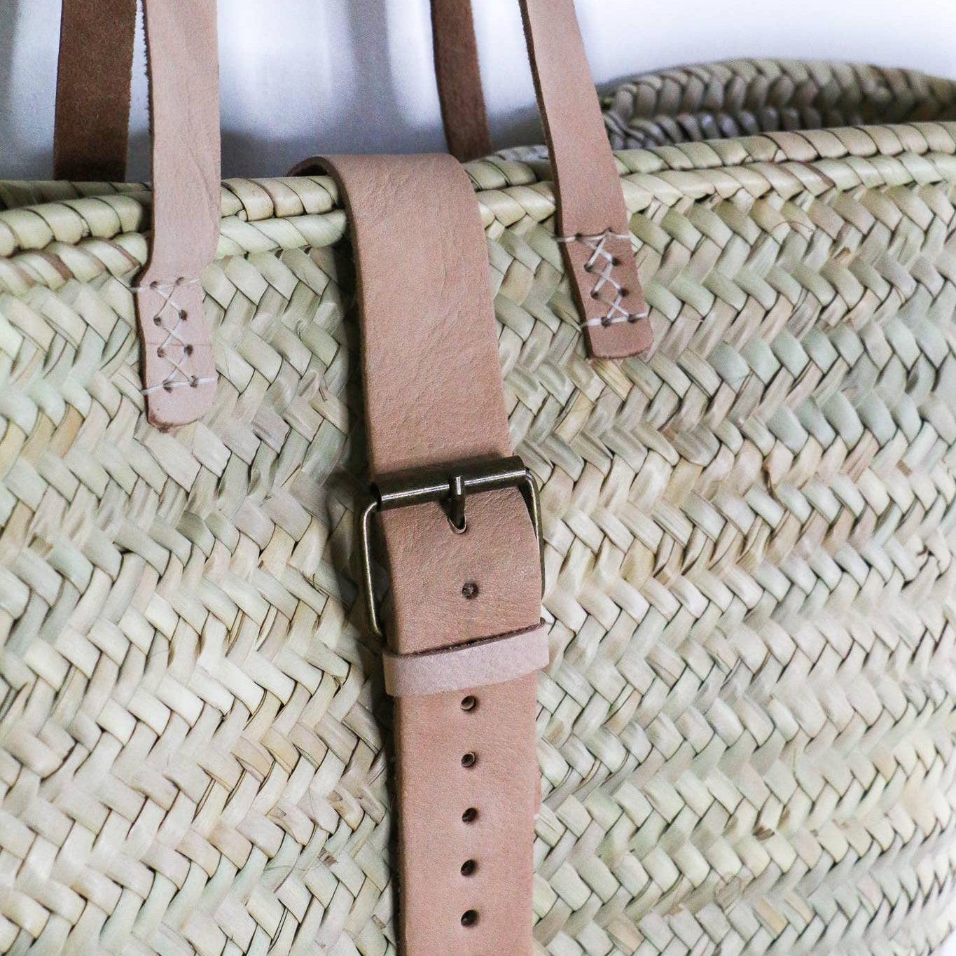 Close-up of the leather buckle closure stitched onto the woven palm basket rim – Medina