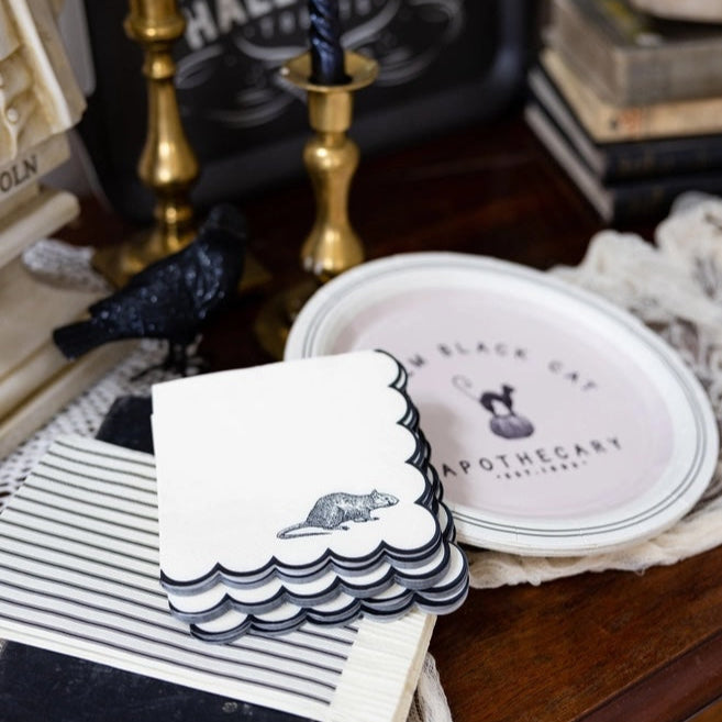 Stack of black and white Napkins with a rodent design on a surface with books and decorative items.