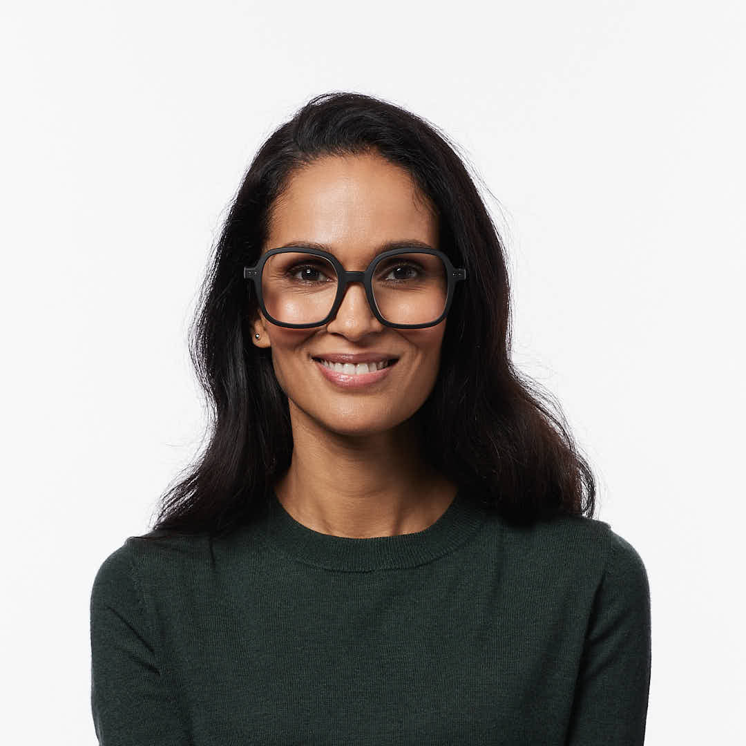 Woman wearing glasses and a dark green shirt on a white background