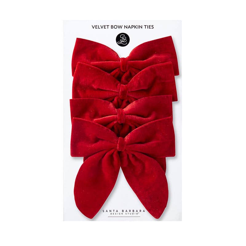 Red velvet bow tied around a cloth napkin on a festive table – Santa Barbara Design Studio