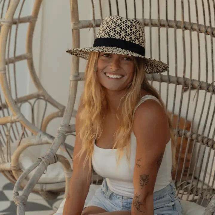 Woman wearing a straw hat sitting on a wicker chair